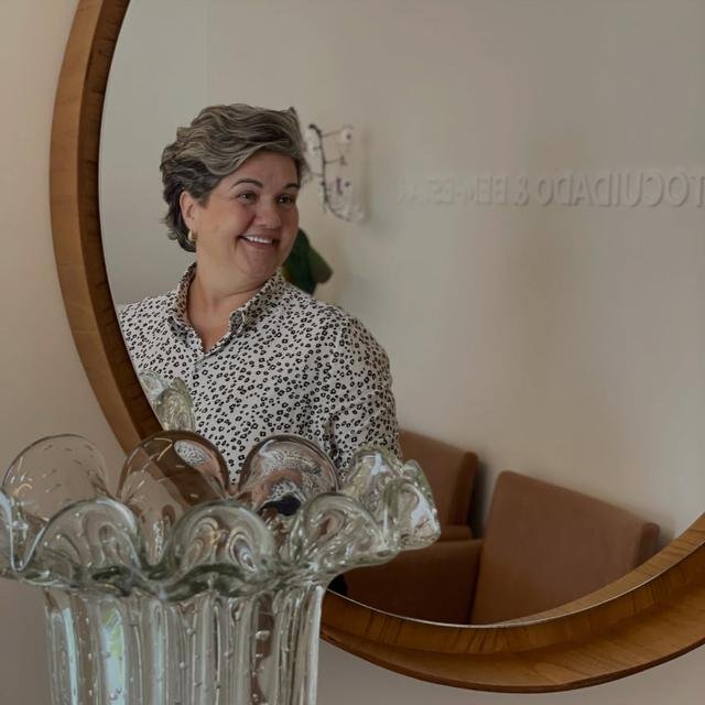 Paciente sorrindo em frente ao espelho na Verdum Odontologia